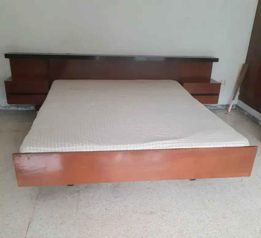 Tempat tidur kayu jati dengan headboard dan nakas. Kokoh
