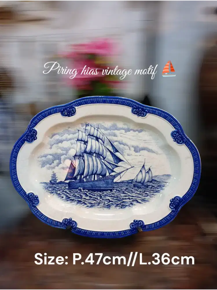 piring hias vintage dengan motif kapal layar berwarna biru dan putih. 