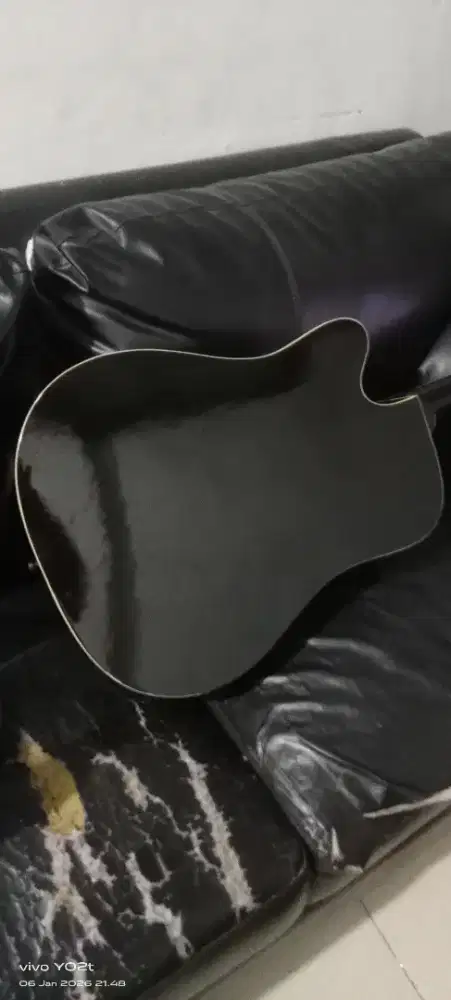 Ini adalah gitar akustik berwarna hitam dengan potongan (cutaway).