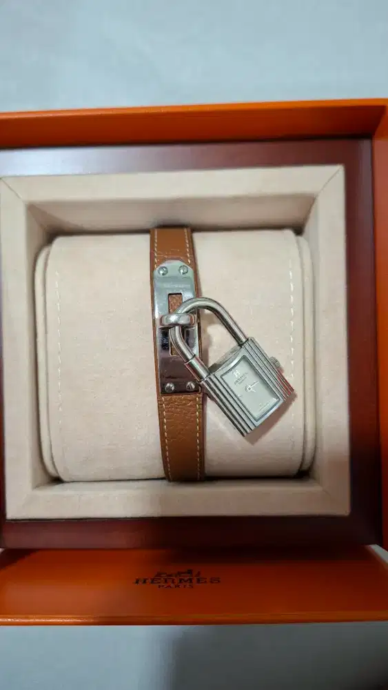 Hermès Kelly dengan tali kulit cokelat dan dial perak.