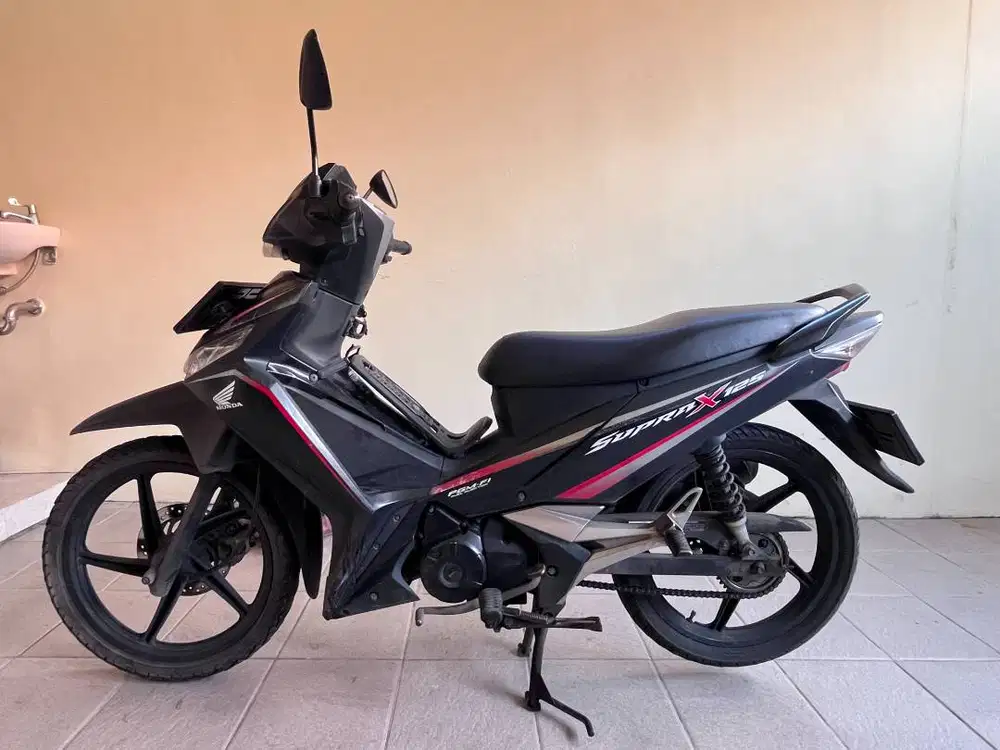 Honda Supra X 125 FI warna hitam, kondisi terawat dan siap pakai.