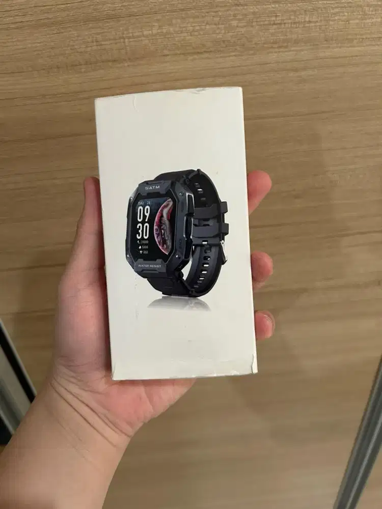 Smartwatch sport model rugged, hitam, layar kotak.