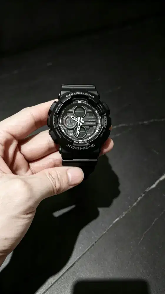 Ini jam Casio G-Shock GA-100-1A1DR (seri GA-100 tampilan hitam polos)
